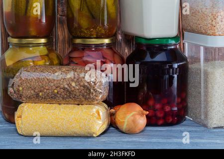 Various types of legumes and cereals in plastic bags on the shelf. Drinks in glass jars, food storage. Crisis, famine, rising prices Stock Photo