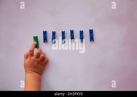 Baby hand picks one stationery clothespins. Curiosity and be different concept. Copy space. High quality photo Stock Photo