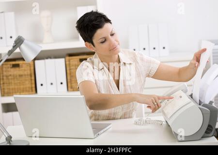 Woman using fax machine Stock Photo