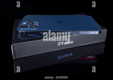Galati, Romania - October 14, 2021: Studio shot of new Apple iPhone 12 Pro Max blue color, back view with Apple logo. Isolate on black glass backgroun Stock Photo