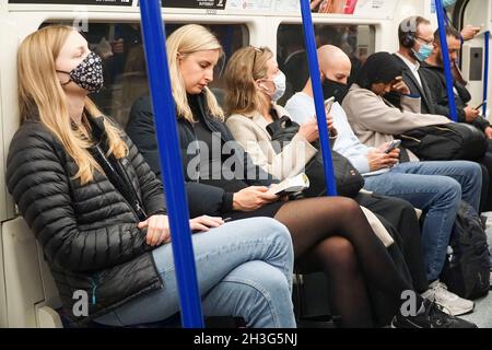 London, UK, 28 October 2021: On the London Underground some people wear face masks but not all do. Although a mask is not required if a person has a medical exemption, large numbers of passengers are travelling without masks despite very high levels of coronavirus transmission and new covid-19 cases. Anna Watson/Alamy Live News Stock Photo
