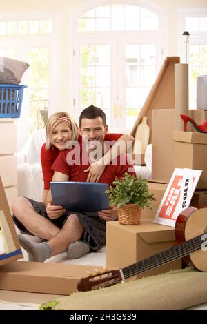 Portrait of couple with computer in new house
