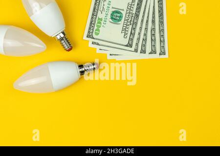 Energy saving. LED light bulbs and money. Yellow background, banner, flat lay Stock Photo