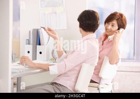 Female office workers sitting at desk Stock Photo