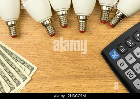 Energy efficiency. Calculating energy efficiency rate concept. Calculator, LED light bulbs and money on wooden table. Top view, flat lay and copy spac Stock Photo