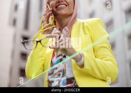 Cheerful young woman talking on cellphone outdoors Stock Photo