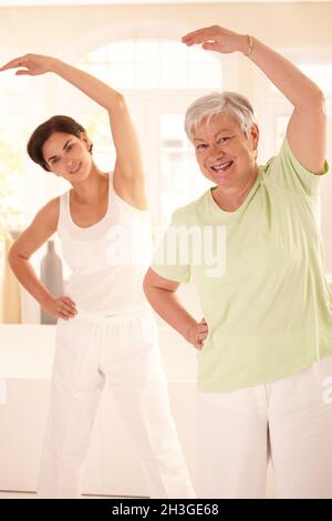 Elderly woman and her personal trainer wearing medical masks during gym ...