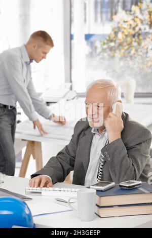 Senior businessman talking on landline phone Stock Photo