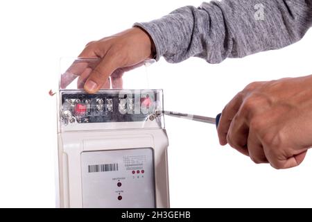 Hands adjusting with screwdriver an electric light meter, isolated on white background. Electrical appliances, electrical tools. Stock Photo
