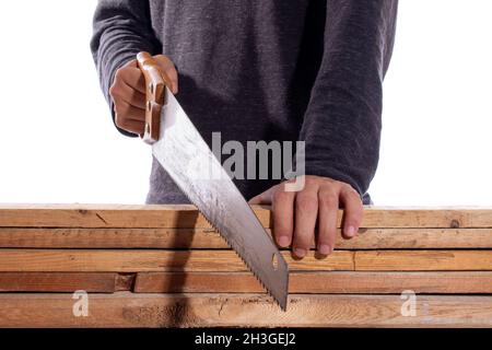 Man cutting wood with hand saw, isolated on white background. Carpenter working with wooden boards. Construction worker. Stock Photo