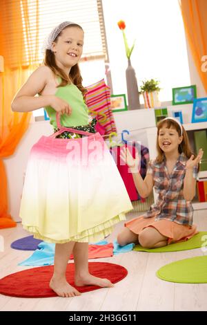 Young girls playing at home fitting dresses Stock Photo