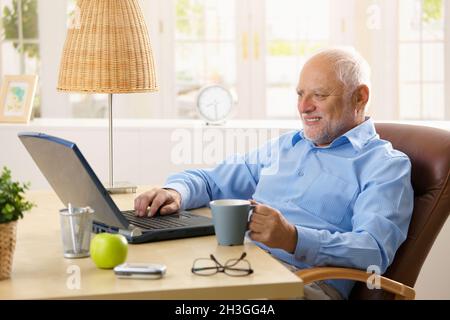 Smiling senior man using laptop Stock Photo