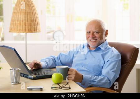 Portrait of happy senior man with computer Stock Photo