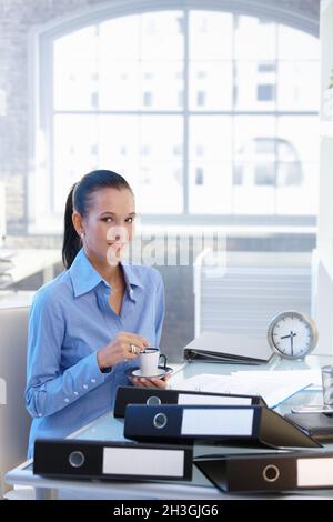 Businesswoman having coffee at desk Stock Photo