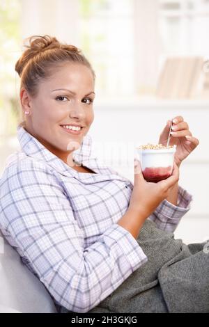 Attractive young woman eating yoghurt in bed Stock Photo