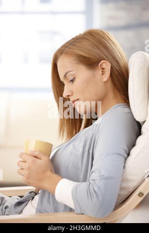 Young woman thinking, holding tea mug Stock Photo