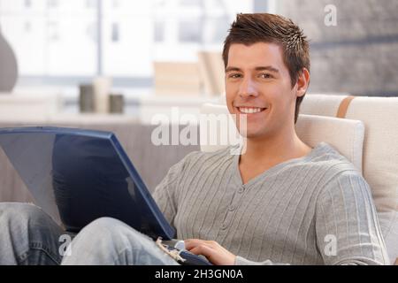Portrait of cheerful young man using computer Stock Photo