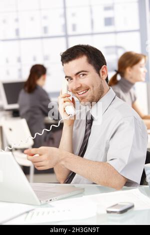 Happy businessman using laptop talking on phone Stock Photo