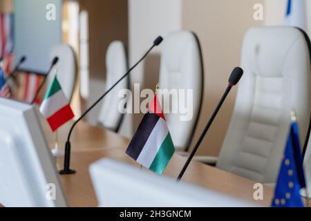 Row of national flags of conference participants from different countries and microphones on long table Stock Photo
