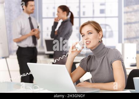 Young woman talking on phone in office smiling Stock Photo