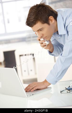 Young office worker on phone using computer Stock Photo