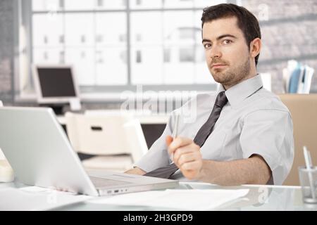 Young man sitting at desk using laptop Stock Photo