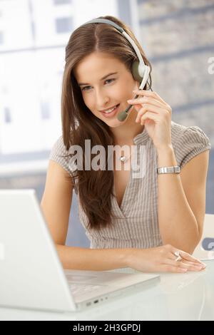 Smiling woman speaking on headset Stock Photo