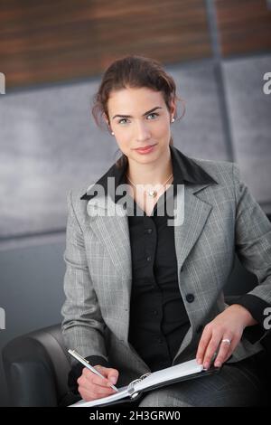 Attractive secretary writing notes smiling Stock Photo