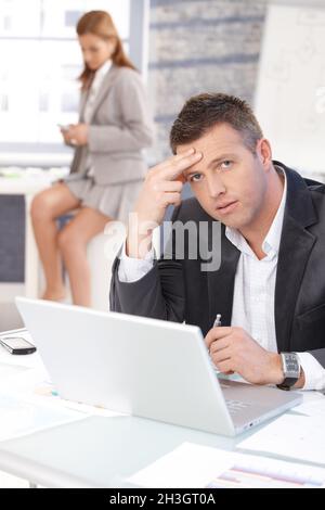 Middle-aged businessman sitting troubled at desk Stock Photo