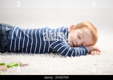 3 year old falling asleep on floor at home Stock Photo