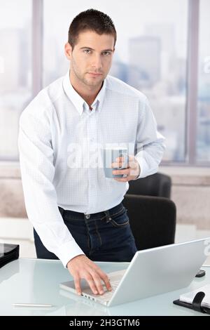Young casual office worker using laptop in office Stock Photo