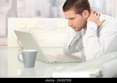 Young man looking tired in office Stock Photo