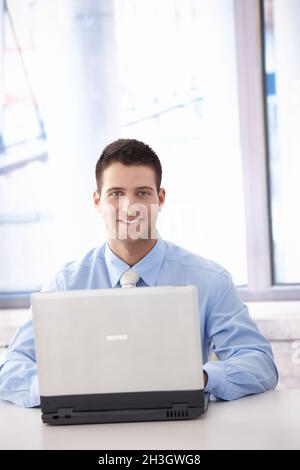 Confident businessman working on laptop smiling Stock Photo