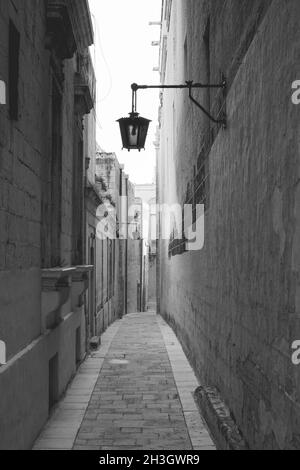 Vertical shot of an alley surrounded by two buildings in Mdina, Malta Stock Photo