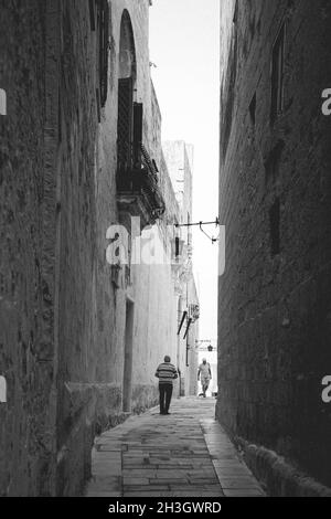 Vertical shot of an alley surrounded by two buildings in Malta Stock Photo