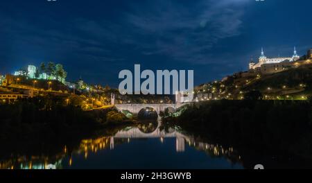 Wide angle view of the View of the Alcantara Bridge across the Tagus River with the Castillo de San Servando on one side and the Alcázar de Toledo on Stock Photo