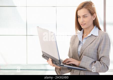 Attractive businesswoman working on laptop smiling Stock Photo