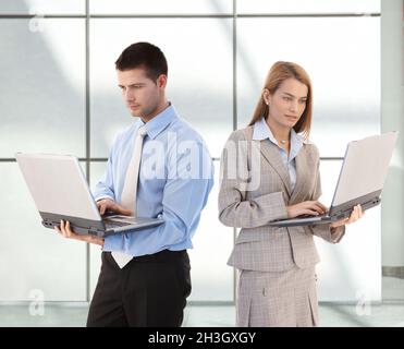 Young businesspeople using laptop in office lobby Stock Photo