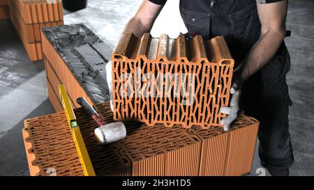 Man puts a brick on a brick wall. Stock footage. Worker on a construction site. Concept of construction Stock Photo
