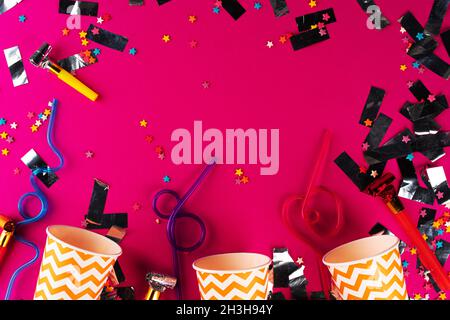 Party tinsel and colorful cups close up on purple background Stock Photo