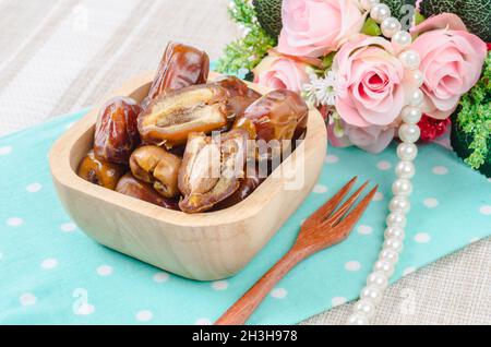 Dried dates fruit in wooden bowl and fork. Stock Photo