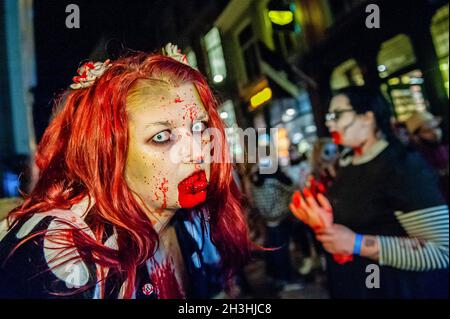 Arnhem, Netherlands. 28th Oct, 2021. A female zombie poses for a photo with her mouth full of fake blood. Last two years the zombie walk was canceled due to the Coronavirus pandemic, however this year, the zombies were allowed to stagger through the inner city of Arnhem in search of fresh brains. The walk started at the Live music venue 'Willemeen', where make-up artists were creating their zombie makeups. Also each year, during the parade, the organization collects animal food, to give to an animal shelter, in Arnhem. Credit: SOPA Images Limited/Alamy Live News Stock Photo