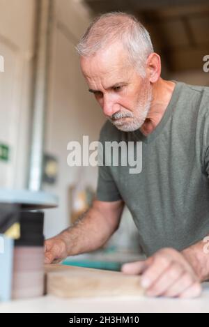 One person sanding the edge of a wooden step Stock Photo