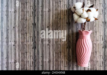 Cotton flowers in a vase close-up on a wooden background Stock Photo
