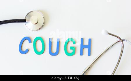 The word cough in wooden letters and with a stethoscope next to it on a white background. Conceptual for healthcare, hospitals, clinics and medical bu Stock Photo