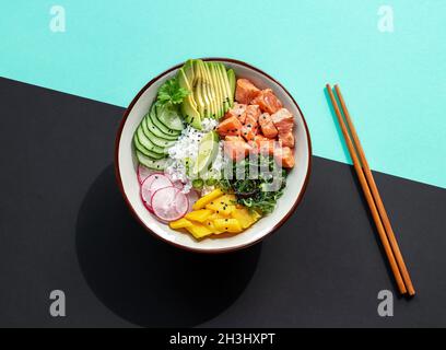 Delicious poke bowl with rice, mango, avocado, radish, chukka salad, cucumber, and marinated fresh salmon.  Stock Photo