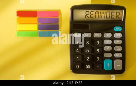 REMINDER text on calculator on yellow sheet with colorful stickers Stock Photo