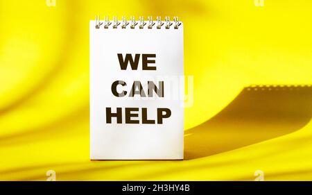 We can help text on white notepad and yellow background Stock Photo