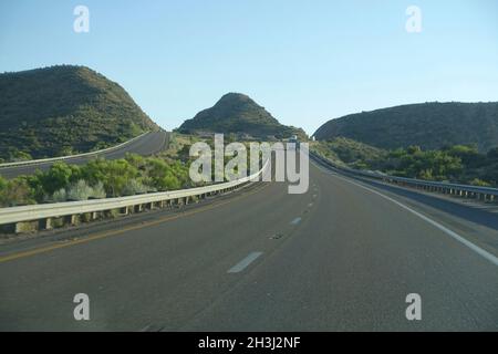Empty highway winding through beautiful green rolling hills. Stock Photo