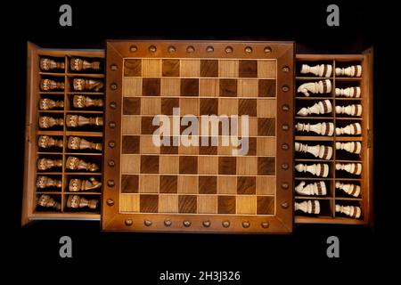 Wooden chess pieces are stacked in a box and photographed from above. A puzzle game with tricky combinations that requires planning and thinking. Stock Photo